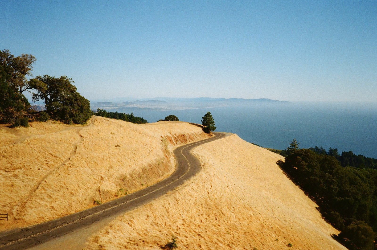 Winding coastal road through golden California hills overlooking the Pacific Ocean