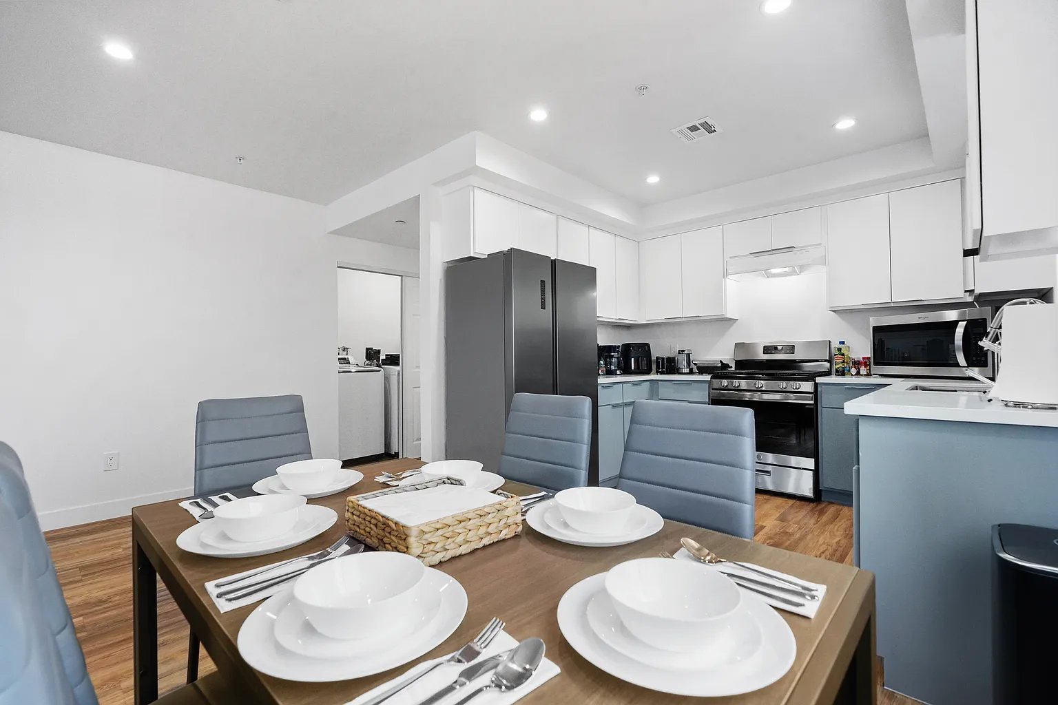 Culver City furnished apartment dining area with set table and fully equipped kitchen with stainless steel appliances