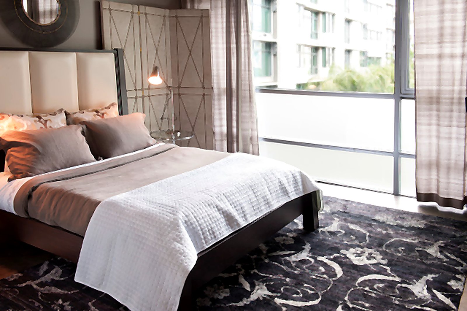 Downtown LA furnished apartment contemporary bedroom with upholstered headboard and designer area rug