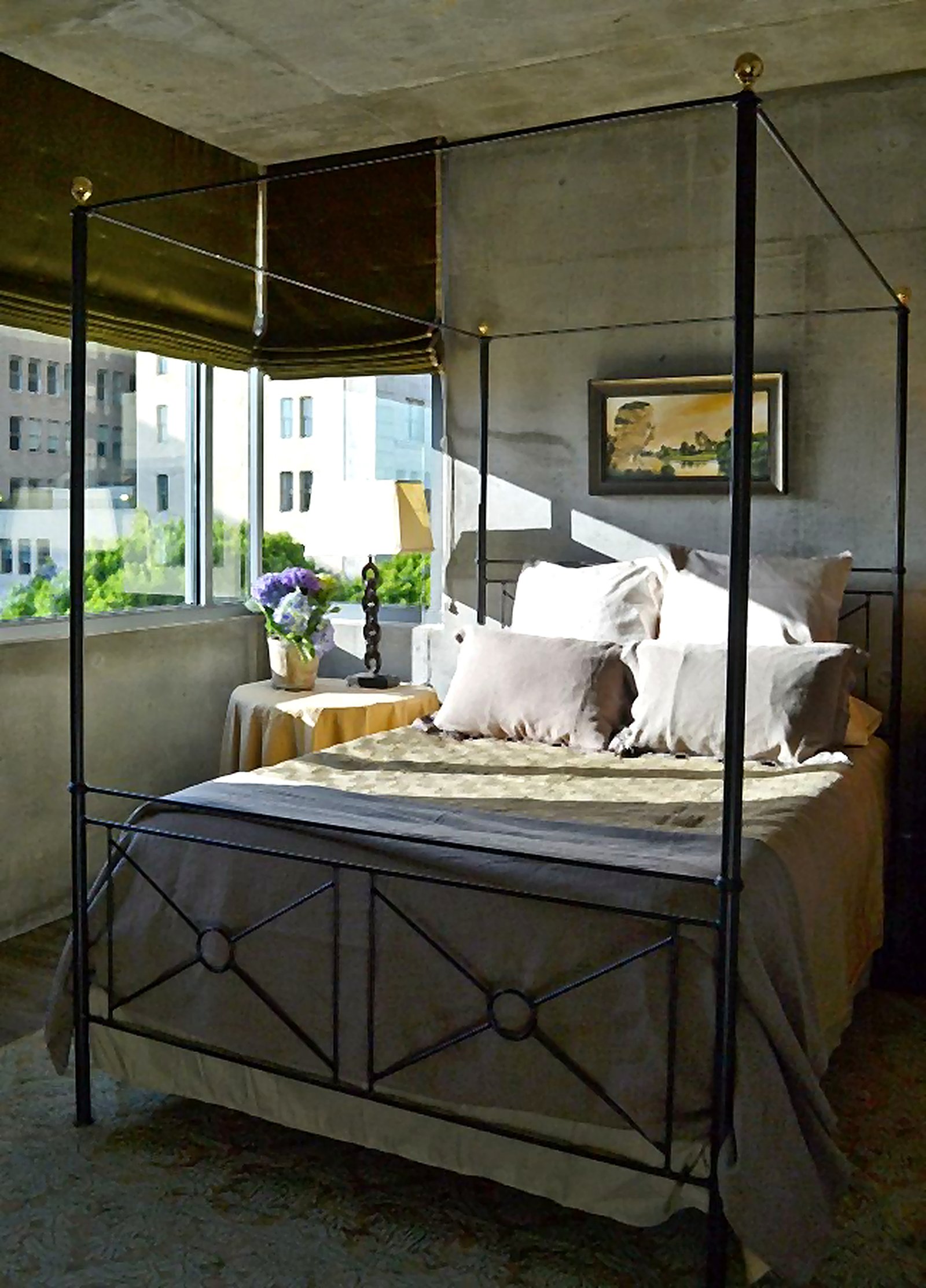 Downtown LA furnished apartment four-poster iron bed with exposed concrete ceiling and city views