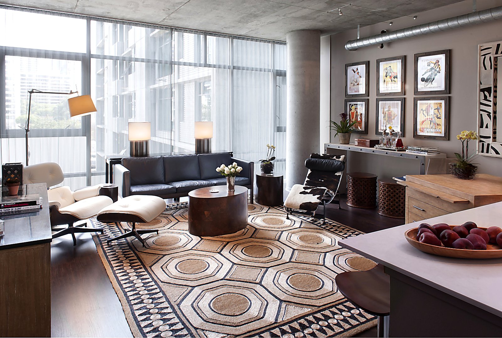 Downtown LA furnished loft living room with Eames chair, gallery wall art, and geometric rug in industrial high-rise