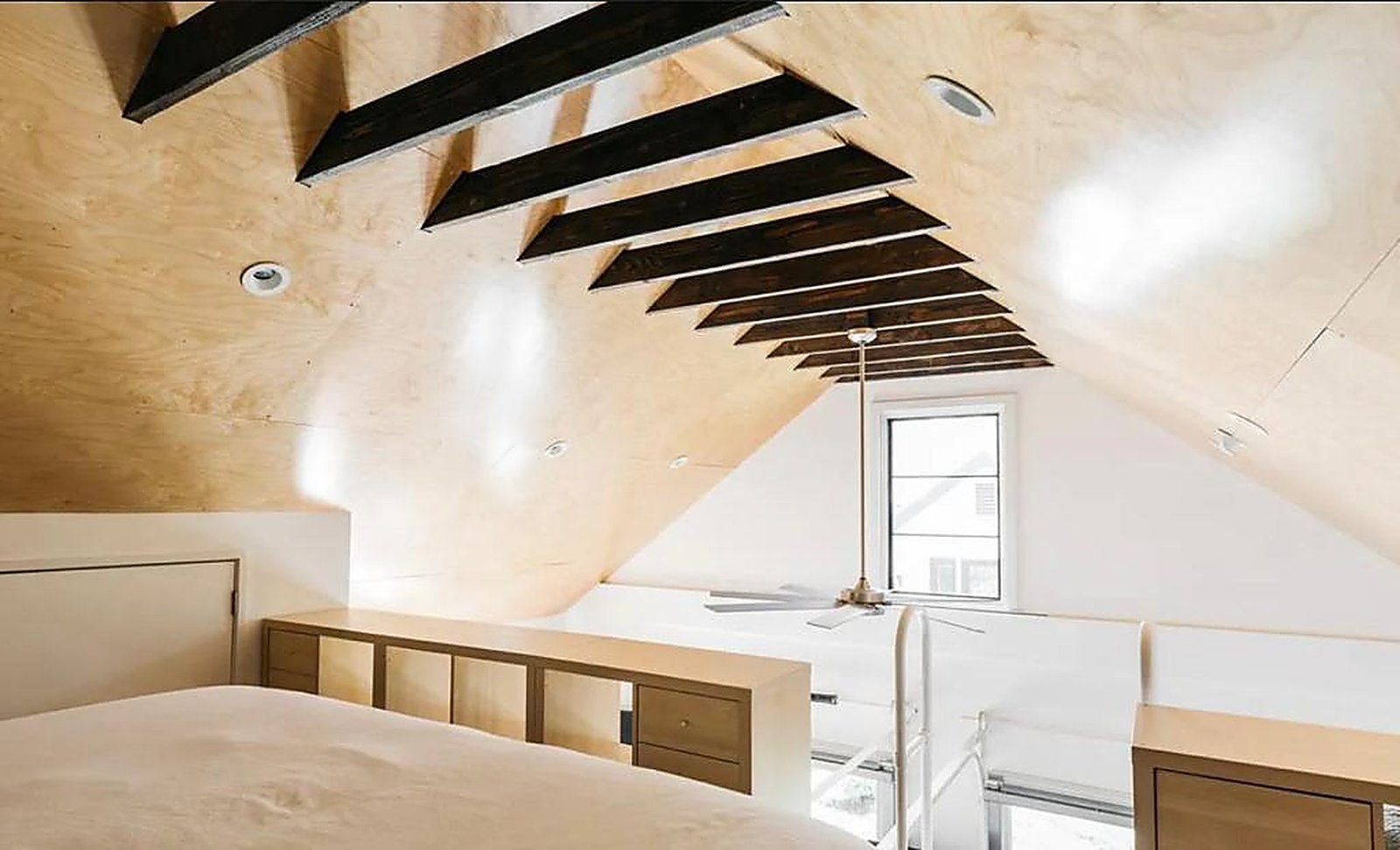 Loft bedroom with exposed wood beams and vaulted ceiling in Santa Monica furnished apartment