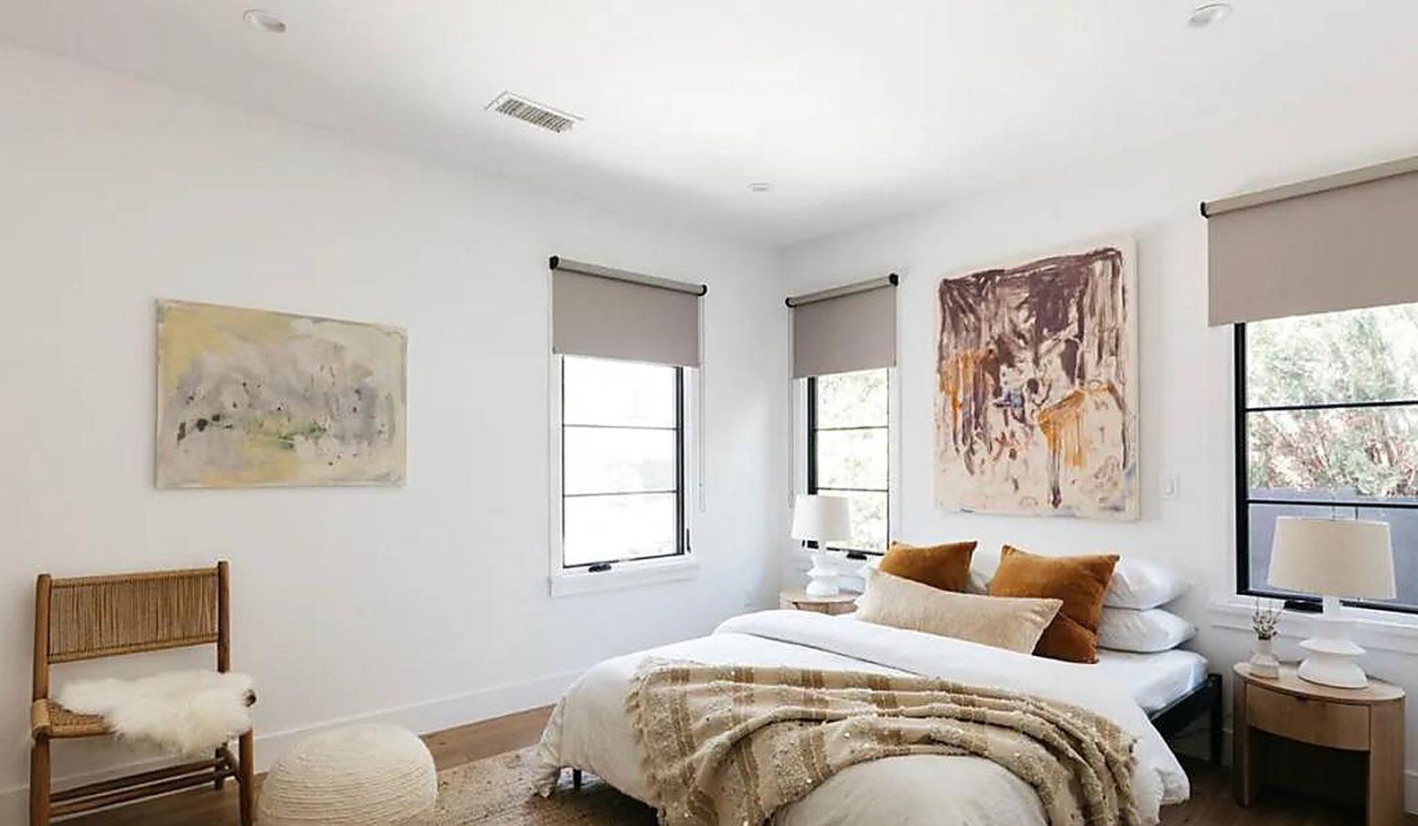 Master bedroom with abstract art and earth-tone bedding in Santa Monica furnished apartment